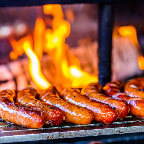 Sausages on a grill with flames in the background