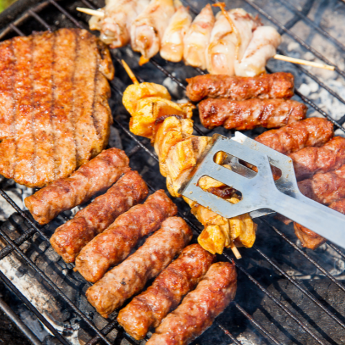 Sausages, steak, chicken kebabs cooking on a bbq