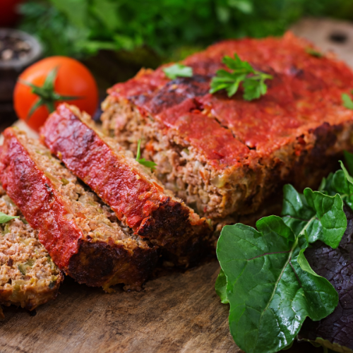 Sliced meatloaf , a tomato and salad leaves