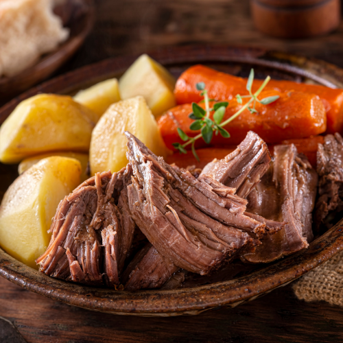 Roast beef, potatoes and carrots on a pottery plate