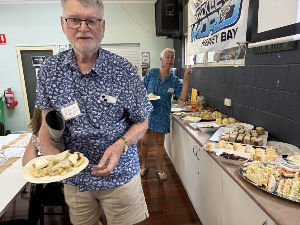 Man and woman helping themselves to a plate of morning tea food